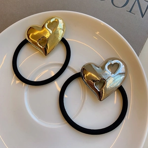 Gold and silver heart-shaped hollow metal hair ties on a white ceramic plate