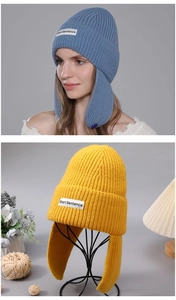 Detail of knitted earmuff beanies in blue and yellow showing thick wool texture and logo