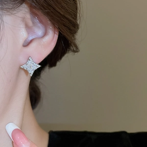 Close-up of sparkling silver star stud earrings with crystals worn by a female model