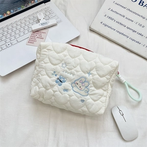 Close-up of white heart quilted makeup bag with blue cloud bunny embroidery and knot zipper