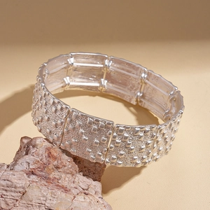 Vue détaillée d'un bracelet large argenté avec maillons et texture quadrillée sur pierre