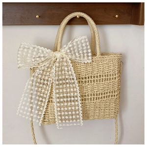 Beige straw woven handbag with large white lace bow and versatile shoulder strap