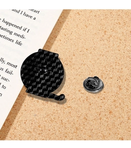 Detail showing the textured metal back and butterfly clutch of the black cat badge