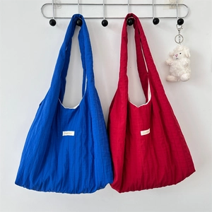 Detail of pleated tote bags in blue and burgundy with vertical stitching and bag charm