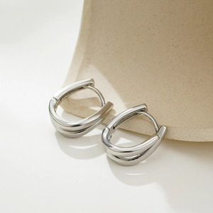 Detail of silver U-shaped hoop earrings with double-layered curved lines design