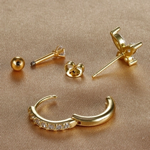 Detail of three-piece gold stud and huggie earring set with sparkling cubic zirconia