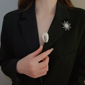 Close-up of stylish silver sunflower and fluid metal brooches on a black suit lapel