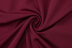Dettaglio del tessuto in maglia a coste rosso scuro con motivo a spirale elegante