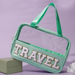 Detail of mint green PVC travel makeup bag with white TRAVEL embroidery and PU handle