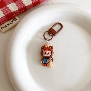 Detail of cute cartoon girl keychain in bear outfit on a white decorative porcelain plate