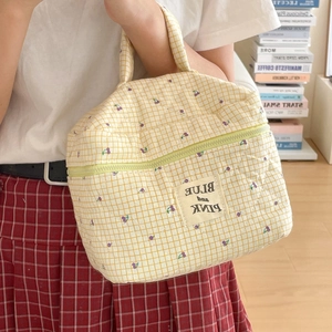 Detail of yellow checkered quilted bag with purple cherry embroidery and woven label