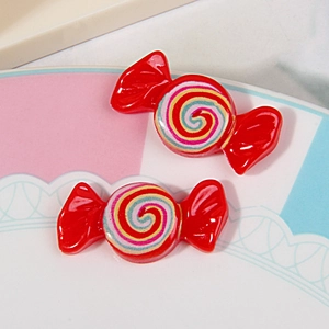 Close-up of two red resin candy charms with colorful spiral pattern for DIY crafts