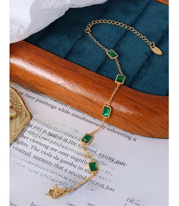 Gros plan d'un bracelet en titane plaqué or 18K avec cinq zircons carrés vert émeraude