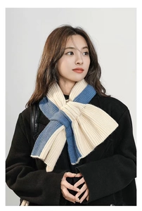 Detailed knit texture of a blue and beige patchwork scarf on a black coat outfit