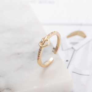 Minimalist adjustable gold heart knot ring with sparkling zircon stones on marble background