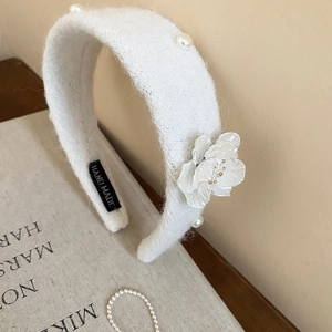 Detail of white plush headband with 3D floral accents and elegant pearl embellishments