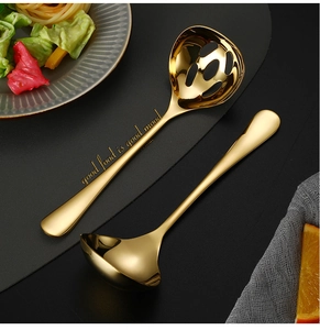 Detail of golden stainless steel soup and slotted spoons with decorative engraving
