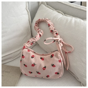 Detail of pink corduroy shoulder bag featuring strawberry embroidery and ruffled strap