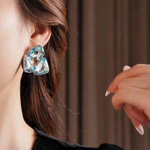 Detail of luxury rhinestone flower earring worn by a model in soft lighting