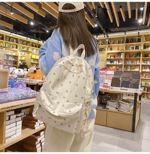 Detail view of floral beige backpack with side pocket in a bookstore scene