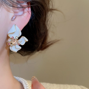 Close-up of floral stud earring with pearl white petals and colorful crystal center