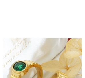 Macro view of a gold-colored ring featuring a round green gemstone with textured band detail