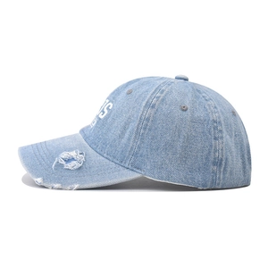 Detailed view of light blue washed denim baseball cap with vintage distressed brim effects