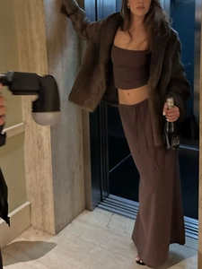 Three-piece dark brown set with fuzzy jacket, crop top, and long skirt in elevator setting