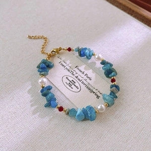 Detail of beaded bracelet with blue stones, imitation pearls and gold extension chain