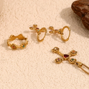 Macro detail of 18K gold plated jewelry set featuring rose cross and colorful crystals