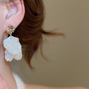 Close-up of elegant flower petal earrings with sparkling rhinestone studs on a model