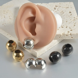 Macro detail of spherical hinge earrings in gold, silver and black on silicone ear model