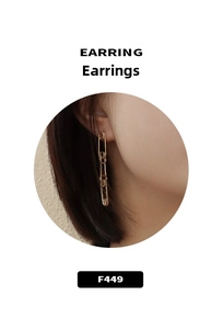 Detail of three-link gold safety pin style earrings in minimalist industrial design