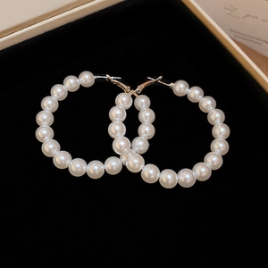Macro shot of large pearl hoop earrings with elegant white beads on black velvet jewelry box