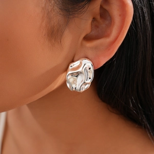Close-up of silver irregular pleated earrings with liquid metal texture on a model