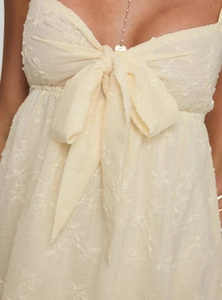 Detail of elegant cream lace dress featuring floral embroidery and a large front bow tie