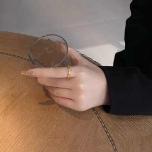Close-up of a 925 silver minimalist gold plated twist ring worn while holding a glass