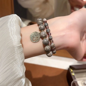 Close-up of double-layer beaded bracelets with grey agate, purple crystal and leaf charm
