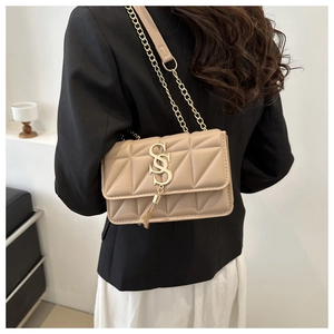 Detail of beige quilted crossbody bag with gold chain strap and metallic tassel logo