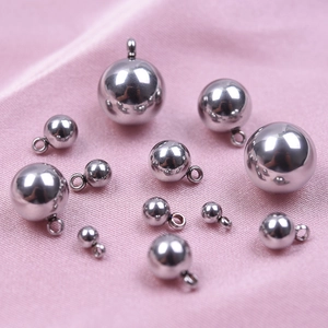 Pendentifs boules en acier inoxydable poli de tailles variées sur un fond de tissu rose doux