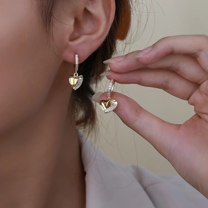 Elegant gold heart drop earrings with shimmering cubic zirconia stones on female model