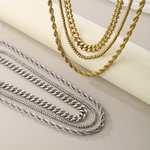 Layered gold and silver stainless steel necklaces featuring curb, rope, and bead chain styles