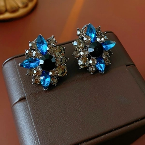 Dettaglio ravvicinato di orecchini vintage a fiore con gemme blu e color talpa