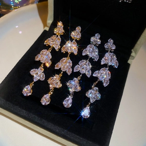 Detail of sparkling leaf tassel earrings with marquise crystals in gold and silver finish