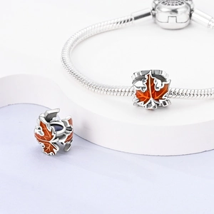 Macro detail of silver maple leaf charm with orange enamel for DIY jewelry making