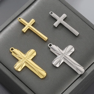 Detail of cross pendants in gold and silver finishes on a grey jewelry display