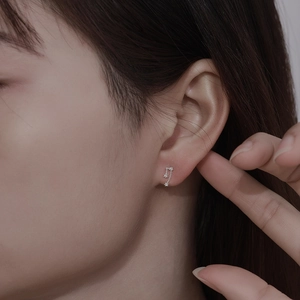 Close-up of 999 sterling silver zodiac earring with zircons on model ear