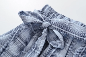 Detail of blue plaid skirt showing elastic waistband and decorative bow tie knot