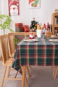 Close-up of festive red and green plaid tablecloth with tassel edges on a wood table