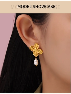 Close-up of elegant gold flower earrings with white freshwater pearl pendants on model